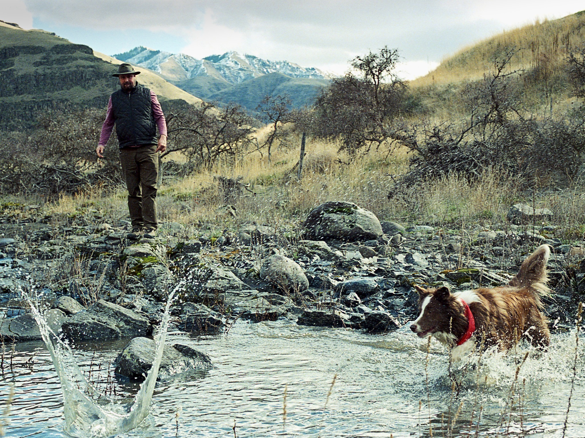 A man and dog crossing a mountain stream